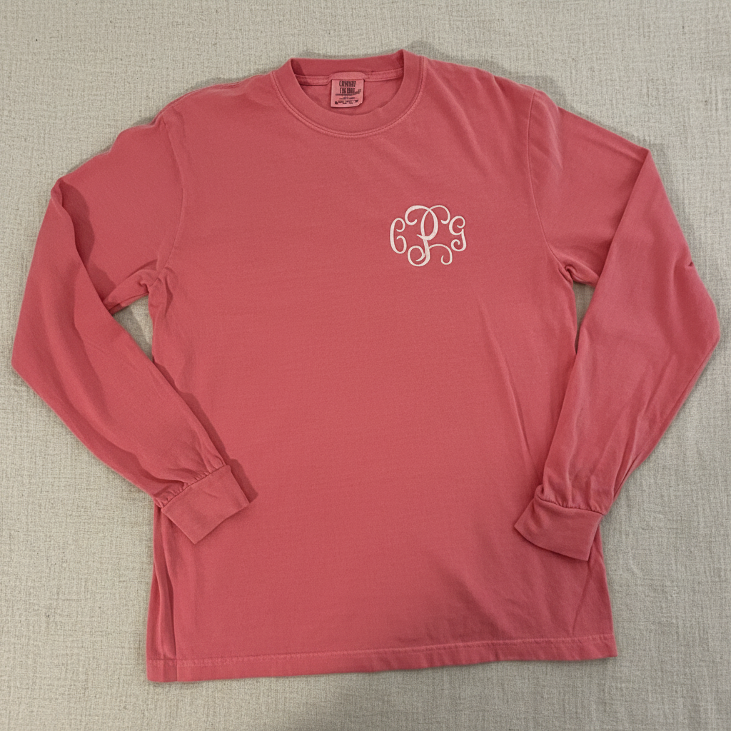 A dusty rose long-sleeve t-shirt with a white cursive monogram logo on the left chest, displayed flat against a white background.