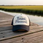 A two-tone trucker hat with a cream front panel and dark navy brim and mesh back, featuring the words 'Mount Pleasant' embroidered in a dotted script across the front.